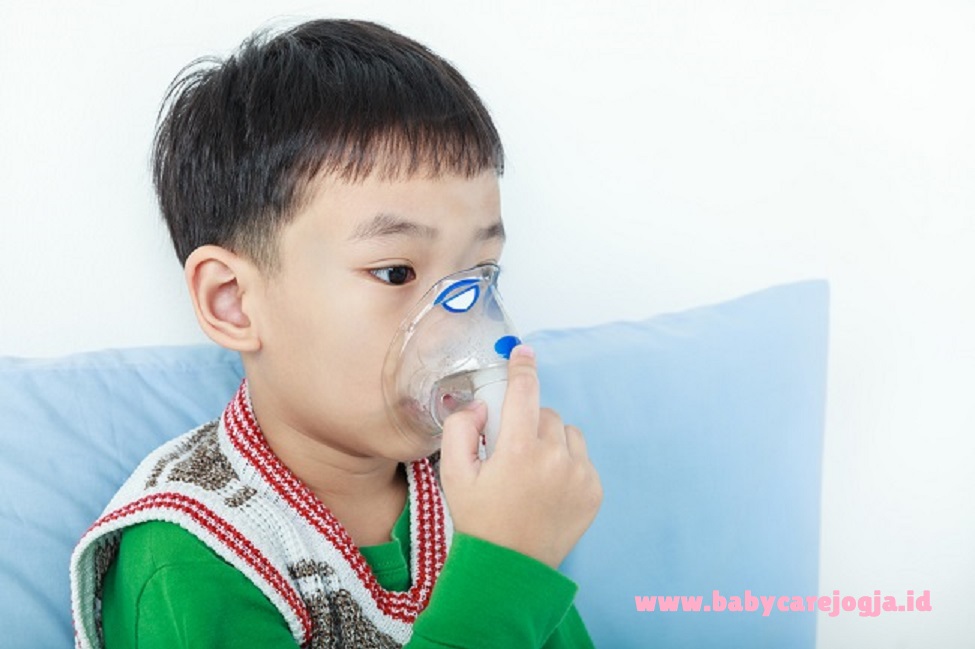 Asian child holds a mask vapor inhaler for treatment of asthma.